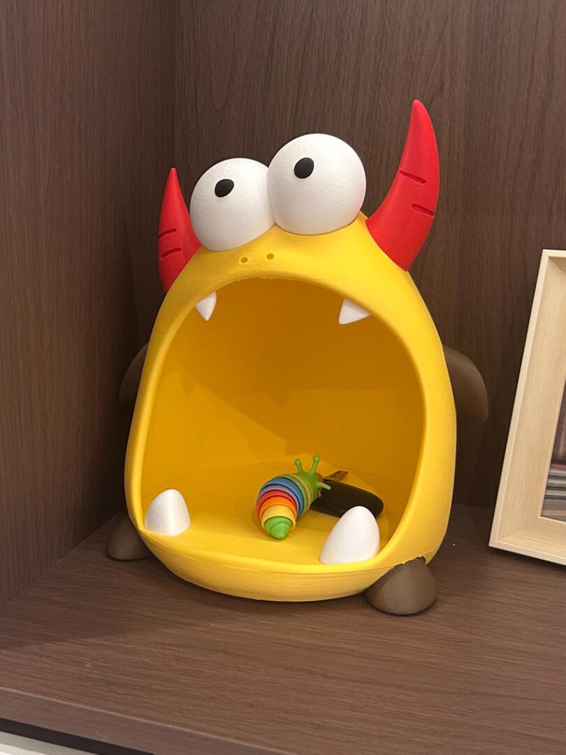 Yellow monster-shaped organizer on a wooden shelf