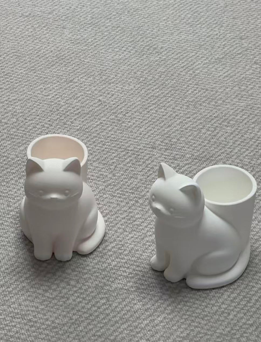 Two white cat-shaped holders on a gray surface