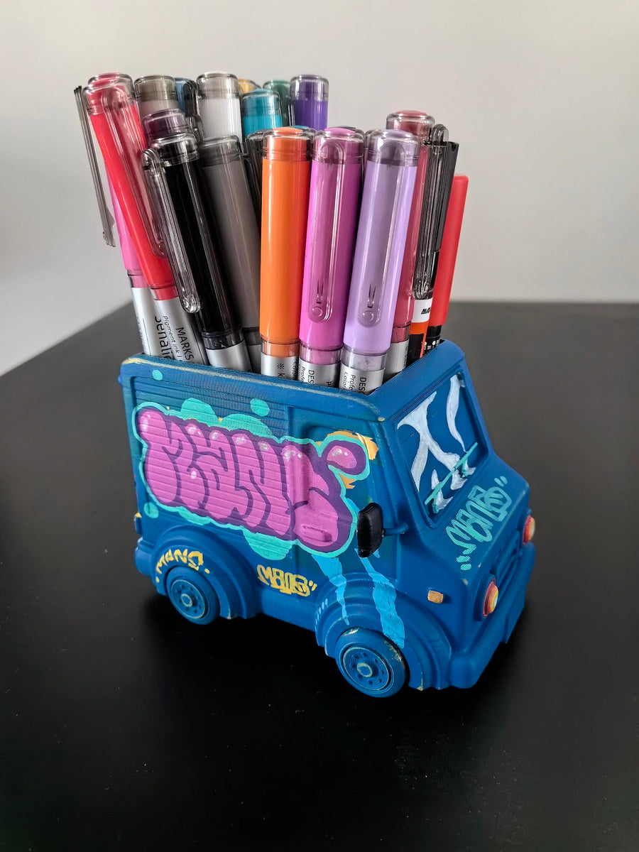 Blue graffiti-covered truck-shaped holder filled with colorful markers