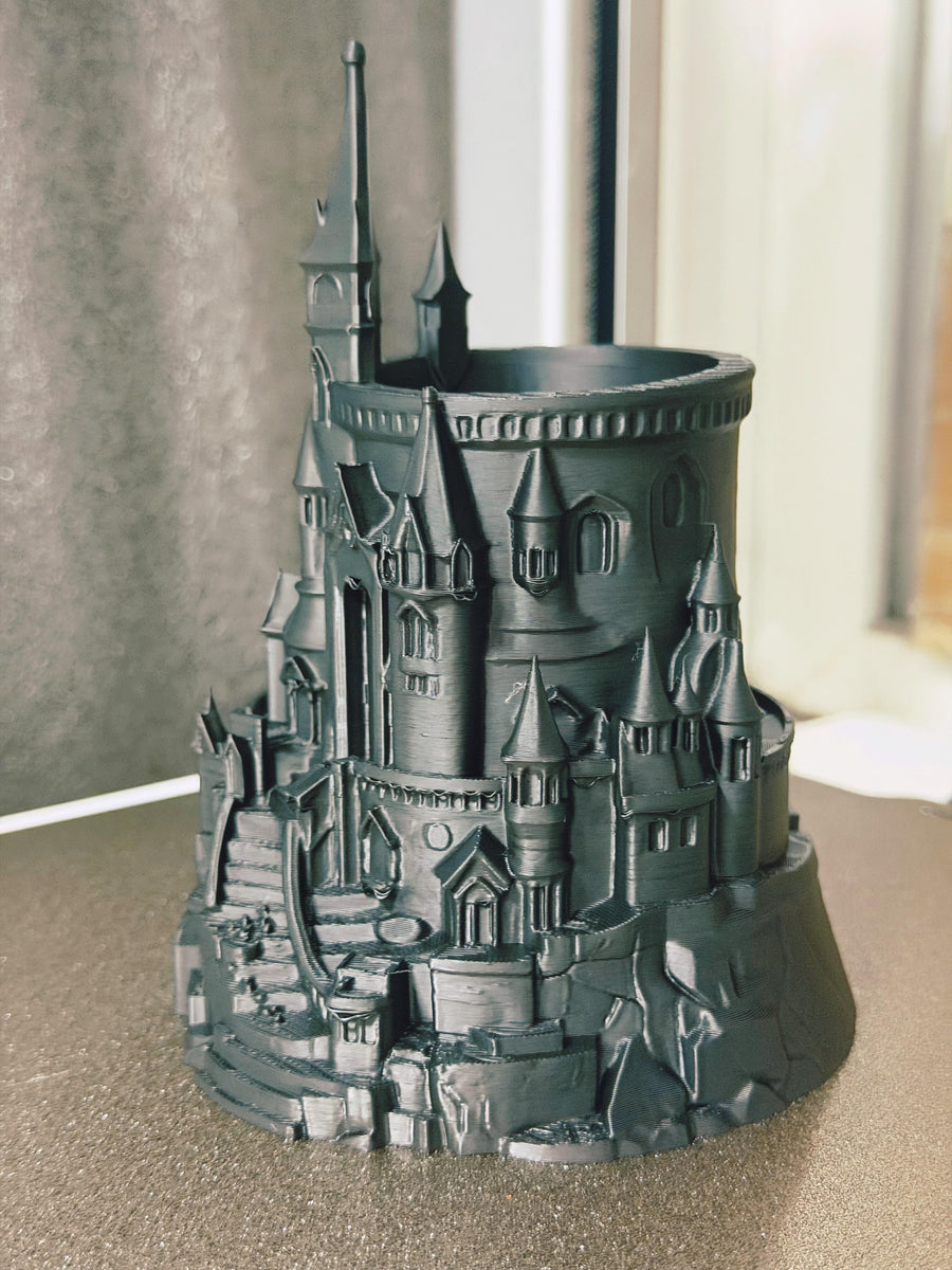 Dark castle-shaped pen holder beside a window