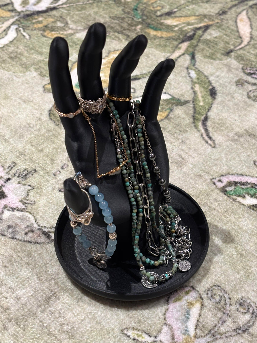 Black hand-shaped jewelry stand displaying necklaces and rings